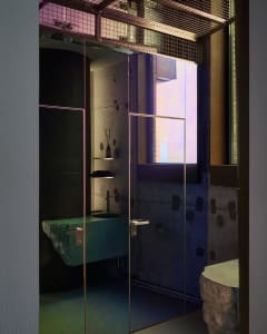 Modern bathroom with a glass shower door, green sink, and two sinks, set against a neutral background
