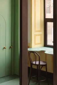 Small room with green walls, yellow trim, two chairs, and a window providing natural light