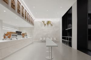 Empty restaurant interior with a large white countertop, chairs, and two dining tables in a clean and well-lit space