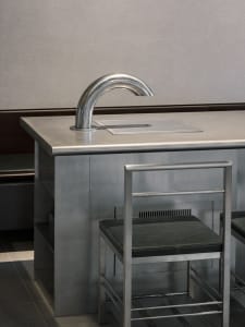 Modern kitchen dining space with a metal sink and wooden dining table, two chairs, and a sleek design