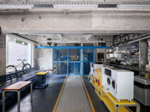 Industrial open space with a yellow walkway, benches, and bicycles, showcasing the interior design and layout of the building