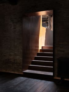A real photo of a staircase leading to another level in a building with wooden steps, warm and inviting atmosphere, and possible sunlight from windows