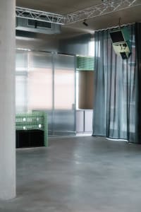 A calm and inviting living area with a green wall, black countertop, and two large TV screens mounted on the wall