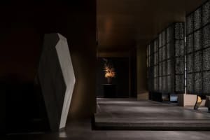 Elegant hallway with a stone wall, marble floor, vases, and a potted plant, creating a sophisticated atmosphere