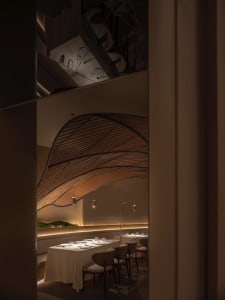 Sophisticated restaurant interior with a long dining table, white linens, and wine glasses, surrounded by chairs in a comfortable atmosphere