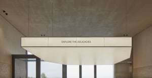 A large white concrete wall with text reading Explore the Delicacies in a modern industrial space