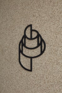 A modern interior space with a brick wall featuring a black metal sign in the shape of a stylized letter P