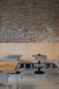 Modern restaurant interior with wooden tables, brick walls, and comfortable seating for guests