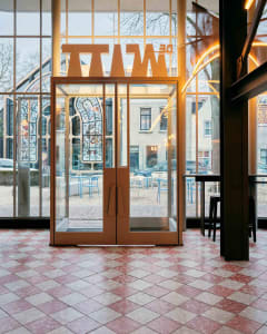 A welcoming entrance with a glass door, multiple chairs, and dining tables, set in a well-lit space