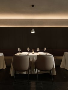 A formal dining area with a large table and chairs, wine glasses, and neatly arranged utensils, set in a sophisticated and inviting atmosphere