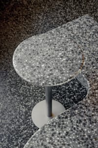 Modern dining space with a round table and chair on a black and white checkered tile floor, suggesting a stylish and possibly restaurant or cafe setting