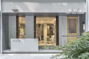A cozy cafe interior with large windows, chairs, and potted plants, inviting a warm and comfortable atmosphere