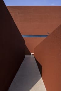 A long hallway with a brown brick wall, concrete floor, and two benches, creating a functional yet somewhat dull atmosphere