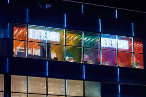 Bright office space with a large glass window, neon sign, and modern furniture