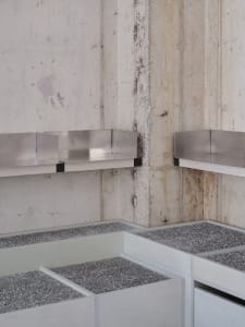 Industrial bathroom with concrete block wall, metal sinks, and minimalist design