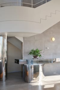 A modern metal staircase with a potted plant on the landing, set in a clean and well-maintained space with good lighting