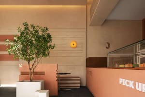 Warm and inviting restaurant interior with pink walls, a tree, a dining table, and a couch, creating a welcoming atmosphere for guests