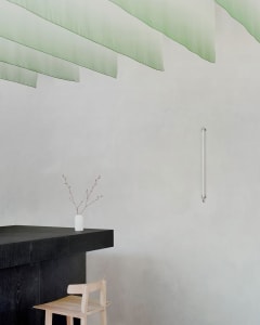 A modern kitchen with a clean and organized atmosphere, featuring a countertop, sink, vases, and a chair, with a focus on functionality and aesthetics