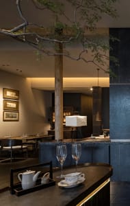 Modern restaurant interior with dining and bar areas, wine glasses, and comfortable seating