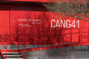 A red building with a staircase leading to a second floor, featuring railings and a possible restaurant or bar design