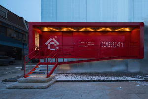 A modern building with a red exterior, a large glass wall, and a contemporary design
