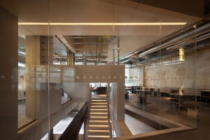Open modern space with a glass wall, wood flooring, and natural light, featuring a dining table and multiple chairs