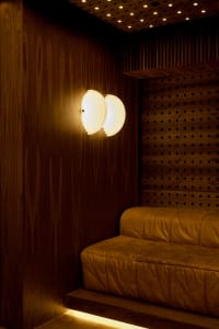 Cozy living space with a wooden wall, a leather couch, and soft lighting from wall-mounted lamps