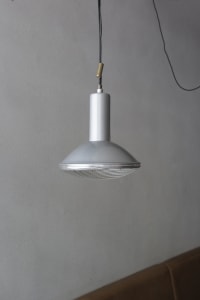 A modern room with a unique lamp hanging from the ceiling, surrounded by clean and minimalistic space with a focus on functionality