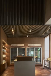 A restaurant kitchen with wooden floors and walls, featuring two refrigerators and scattered bottles, creating a functional and stylish space for cooking and serving meals