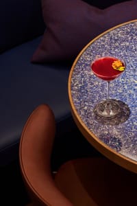 A wooden dining table in a restaurant with two chairs and a glass of red wine, creating a warm and inviting atmosphere
