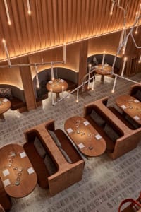 Warm and inviting restaurant interior with wooden floors, dining tables, and comfortable seating, lit by well-placed candles and overhead lighting