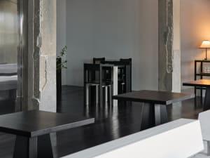 A clean and well-organized restaurant with multiple dining tables and chairs, surrounded by white walls and ready for customers