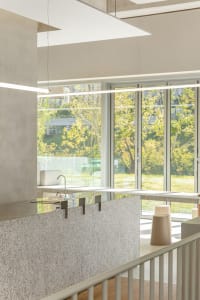 Modern kitchen with large windows, sleek countertops, stainless steel appliances, and two sinks for multiple users