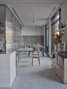 Modern kitchen and dining area with white cabinets, a dining table, chairs, and decorative vases in a clean and minimalist space