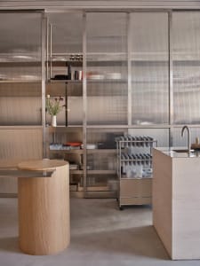 Open kitchen area with a wooden countertop, appliances, and decorative bottles, featuring a clean and organized atmosphere with a focus on functionality