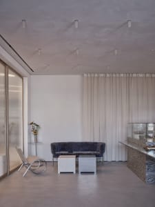 A modern living space with a couch, chair, dining table, and vase, surrounded by white walls and curtains, with a comfortable and inviting atmosphere