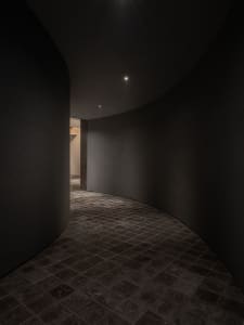A calm and quiet interior hallway with a curved design, made of concrete, and a door leading to another part of the building