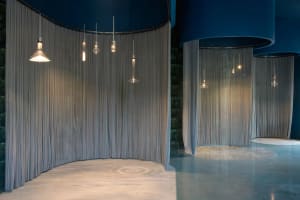 An indoor space with two curtain walls and hanging lights between them, featuring soft and elegant fabric curtains and a sophisticated atmosphere