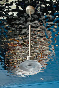 Underwater hotel lobby with a large metal chandelier reflected in the water, surrounded by a captivating atmosphere