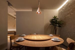 A warm and inviting dining area with a large wooden round table and chairs, set with cups, perfect for socializing and sharing a meal