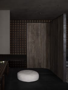 Warm and inviting room with a wooden floor, wooden doorway, and two benches, with a chair placed in the center