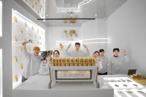 A group of people posing in front of an Arabica coffee machine with various canisters on display, creating a friendly and inviting atmosphere