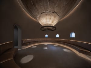 Empty room with a high ceiling, featuring a large circular object and benches for seating, creating a spacious and inviting atmosphere