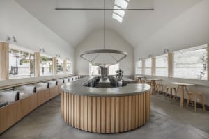 Modern open kitchen with a large island, sink, chairs, and couches, surrounded by modern design elements