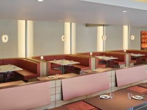 An inviting restaurant interior with multiple dining tables, chairs, and wood elements creating a warm atmosphere
