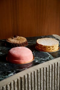 A marble table set with three cakes, each on its own plate, in a celebratory atmosphere
