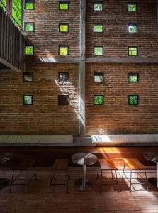A modern restaurant interior with brick walls, wooden accents, and dining tables, creating a warm and inviting atmosphere