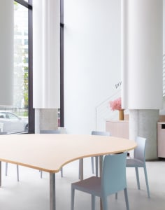A calm and inviting lobby with a wooden dining table and white panelled walls, four chairs placed around the table