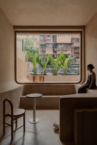 Cozy living space with two benches, a dining table, potted plants, and a chair, creating a warm and inviting atmosphere