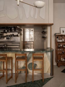 A kitchen with a marble countertop, wooden stools, and three chairs, conveying a warm and inviting atmosphere for gatherings and socializing